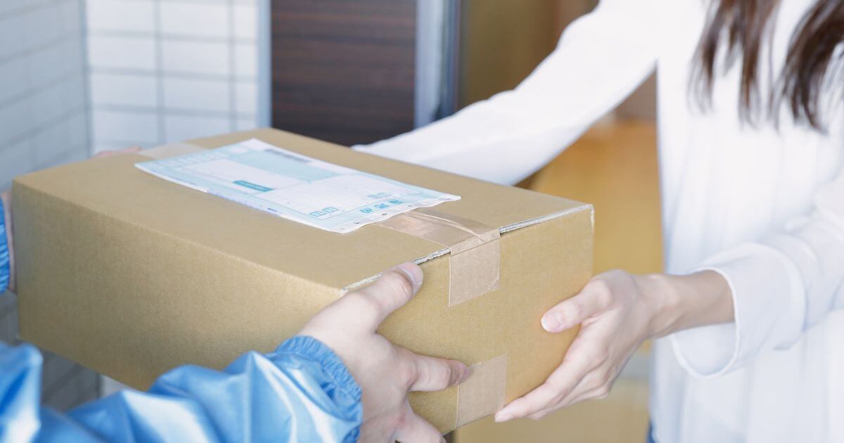 段ボール箱を配達員から受け取る様子